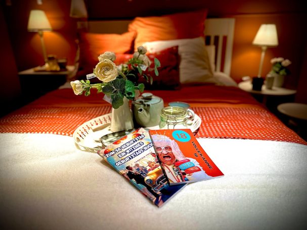 Ein dekoriertes Bett mit einer Zeitschrift und einer Vase mit Blumen auf einem Tablett.